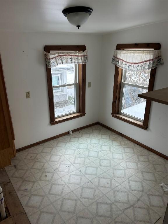 unfurnished dining area featuring baseboards and light floors