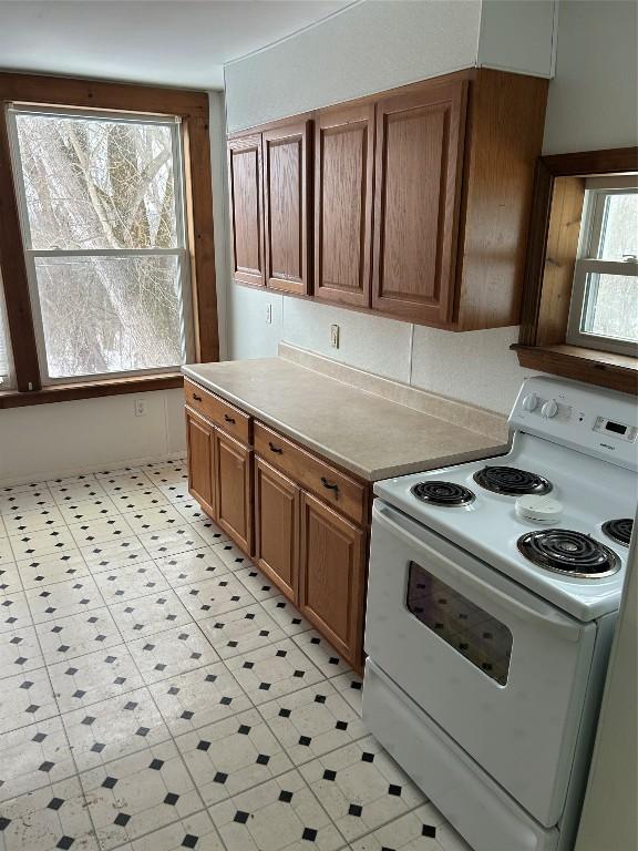 kitchen featuring light countertops, electric range, and brown cabinetry