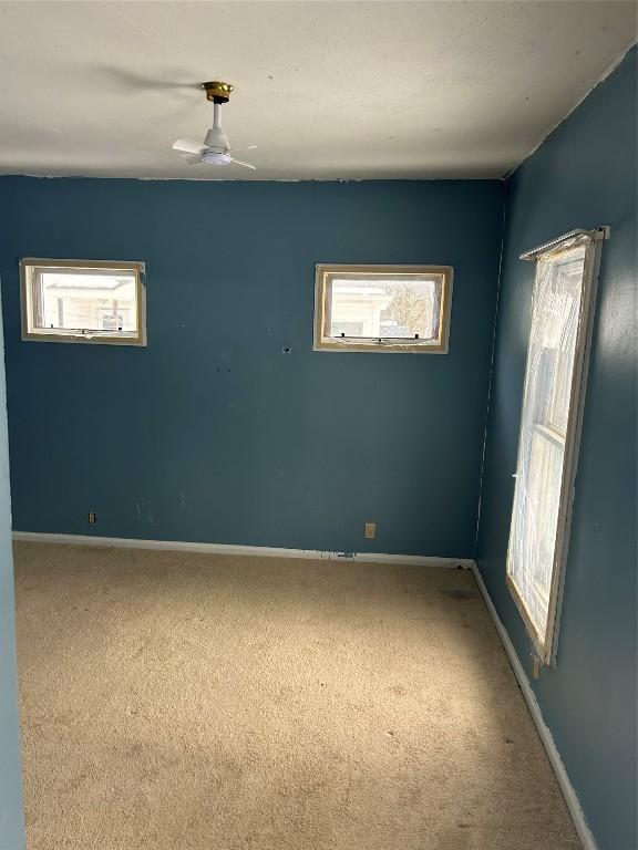 spare room featuring carpet flooring, ceiling fan, and baseboards