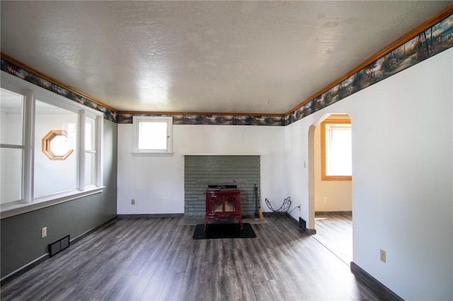 unfurnished living room featuring dark hardwood / wood-style flooring, a wood stove, and a textured ceiling