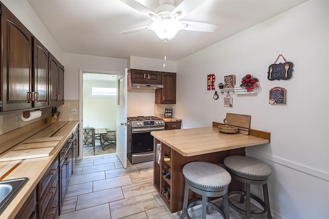 2548 E 32nd St, Erie, PA 16510 - kitchen featuring stainless steel range with gas cooktop, a kitchen bar, dark brown cabinets, ceiling fan, and butcher block countertops