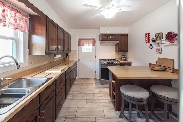 2548 E 32nd St, Erie, PA 16510 - kitchen featuring stainless steel range with gas cooktop, a breakfast bar area, a ceiling fan, butcher block counters, and dark brown cabinets