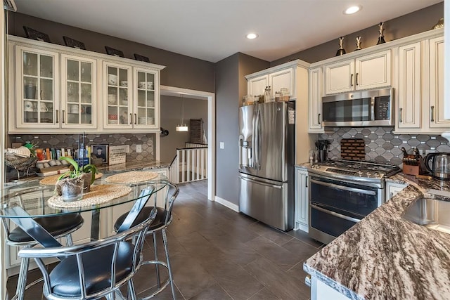 kitchen featuring recessed lighting, stainless steel appliances, baseboards, decorative backsplash, and glass insert cabinets