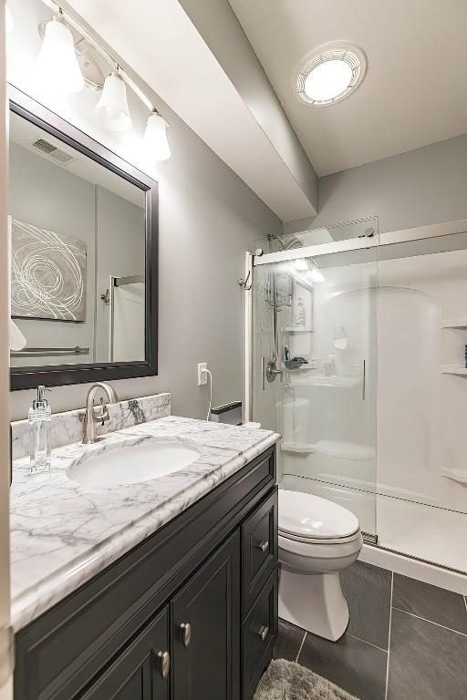 full bathroom featuring a stall shower, visible vents, toilet, tile patterned floors, and vanity