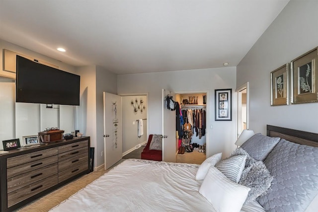 bedroom featuring a closet, light colored carpet, a spacious closet, and baseboards