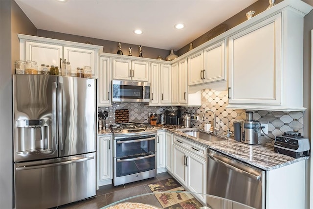 kitchen with stone counters, stainless steel appliances, recessed lighting, backsplash, and a sink