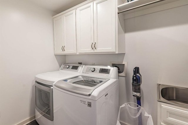 washroom featuring a sink, washing machine and dryer, and cabinet space