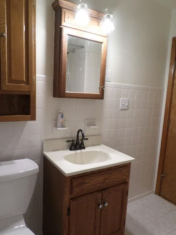 bathroom with tile patterned floors, vanity, toilet, and tile walls