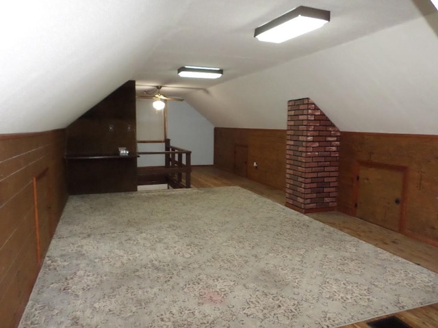 bonus room with vaulted ceiling and wooden walls