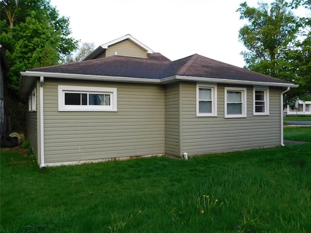 view of side of home with a yard and a shingled roof