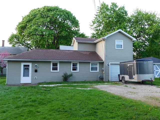 rear view of property featuring driveway, a lawn, roof with shingles, and a garage