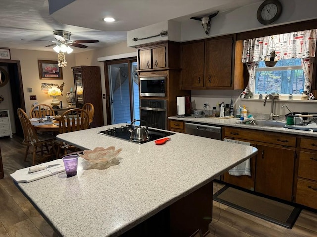 kitchen with a center island, dark wood-type flooring, sink, ceiling fan, and appliances with stainless steel finishes