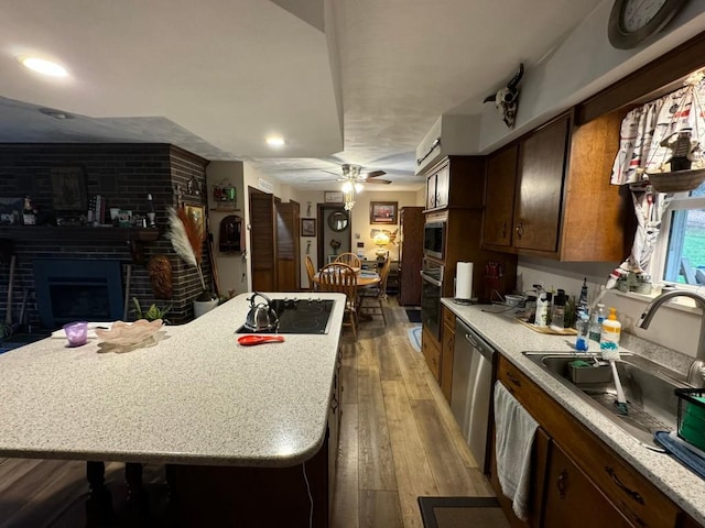 kitchen featuring ceiling fan, sink, stainless steel appliances, a fireplace, and a kitchen island