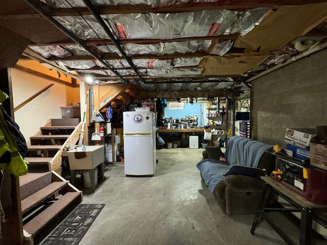 basement with a workshop area and white fridge