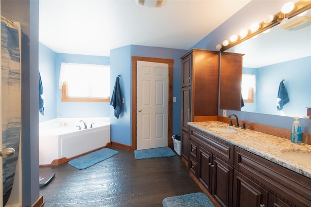 bathroom with hardwood / wood-style flooring, vanity, a bathing tub, and a wealth of natural light