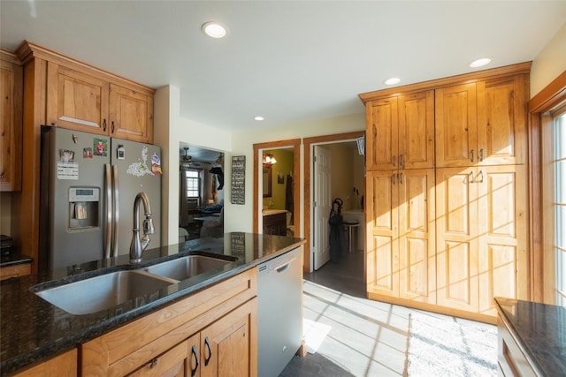 kitchen with appliances with stainless steel finishes, sink, and dark stone countertops