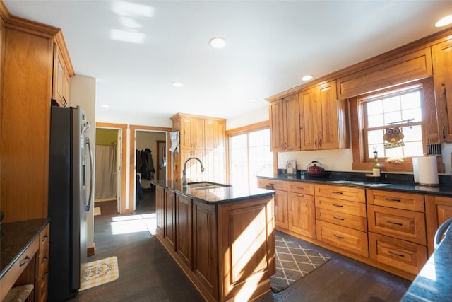 kitchen with dark hardwood / wood-style floors, sink, dark stone countertops, and stainless steel refrigerator