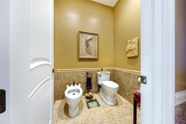 bathroom with tile patterned floors, a bidet, tile walls, and toilet