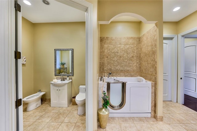 bathroom featuring washing machine and dryer, a bath, tile patterned floors, a bidet, and toilet