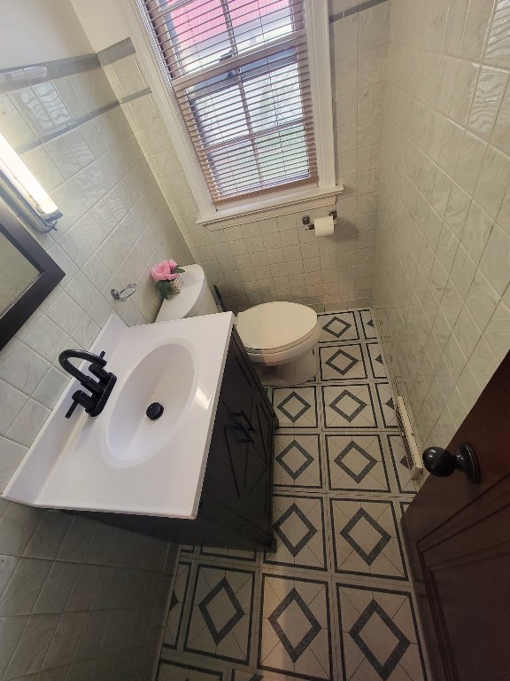 bathroom featuring tile patterned floors, tile walls, and toilet