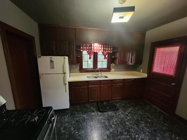 kitchen featuring black gas range, white refrigerator, and sink