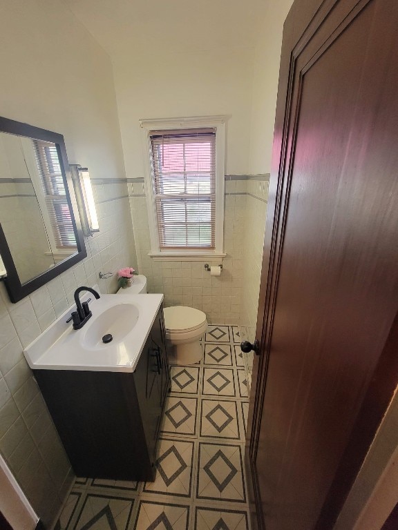 bathroom with vanity, tile walls, and toilet