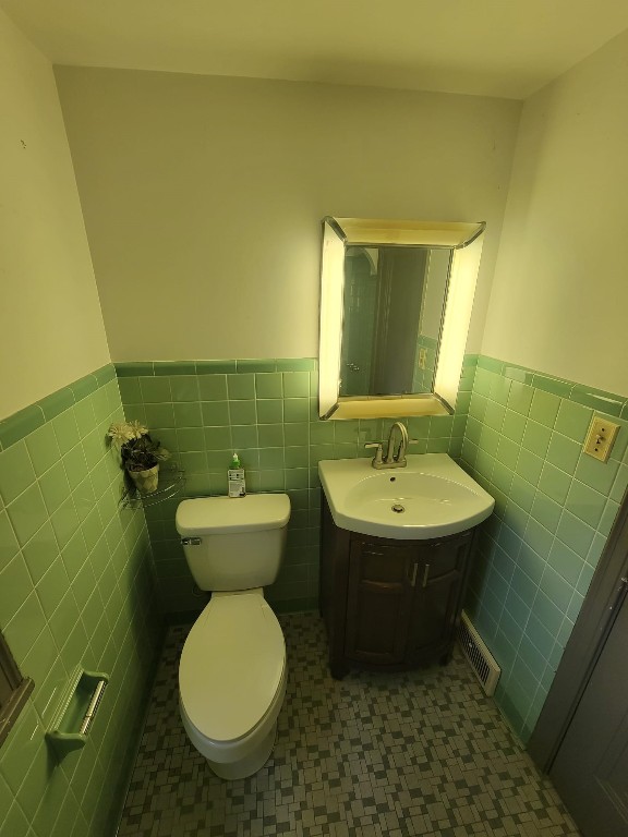 bathroom featuring tile patterned floors, vanity, tile walls, and toilet