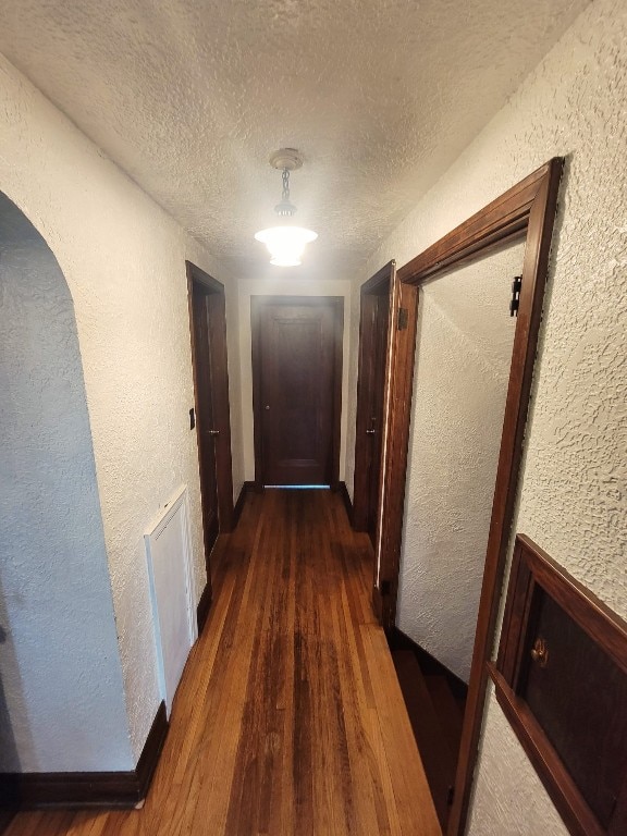 hall featuring a textured ceiling and dark hardwood / wood-style floors