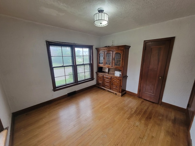 empty room with light hardwood / wood-style flooring and a textured ceiling