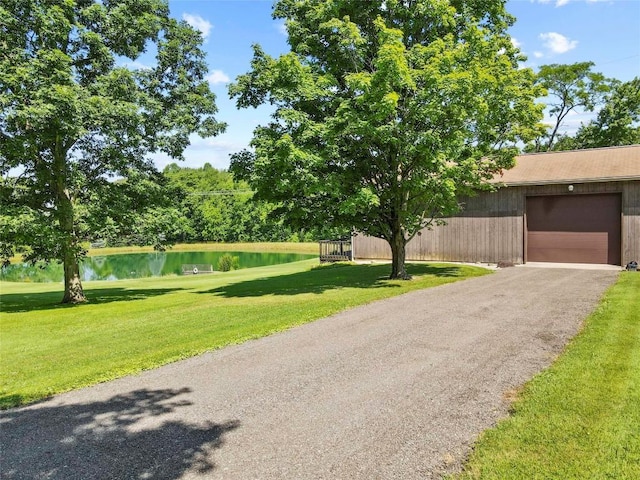 6946 Huntley Rd, West Springfield, PA 16443 - view of front of house featuring a front yard, a water view, asphalt driveway, an outdoor structure, and an attached garage