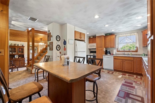6946 Huntley Rd, West Springfield, PA 16443 - kitchen with white appliances, a breakfast bar, recessed lighting, light countertops, and brown cabinetry