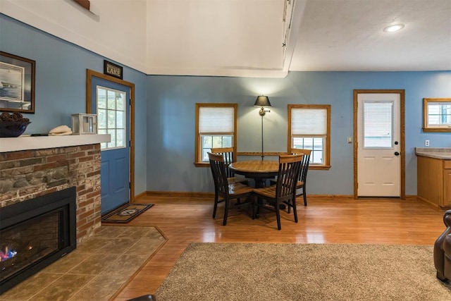 dining space with light hardwood / wood-style flooring, plenty of natural light, and a brick fireplace