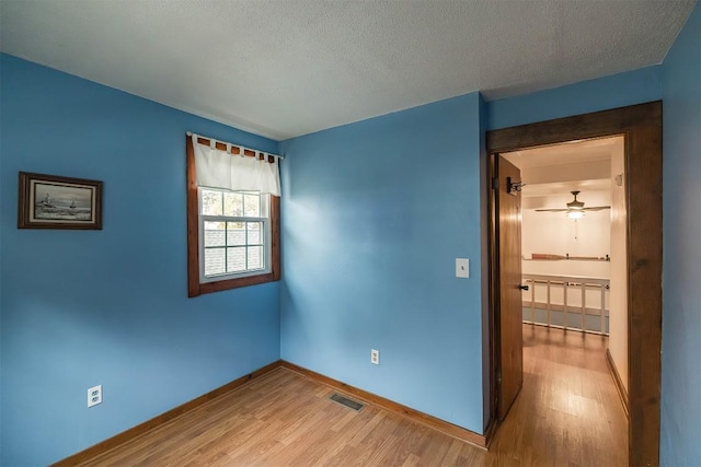 spare room with ceiling fan, a textured ceiling, and light hardwood / wood-style flooring