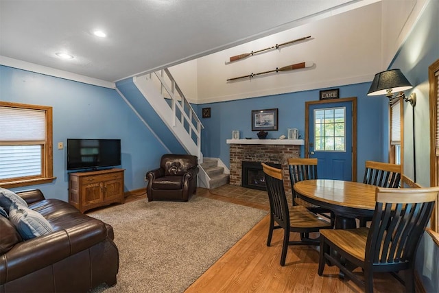 living room with wood-type flooring, a brick fireplace, and lofted ceiling