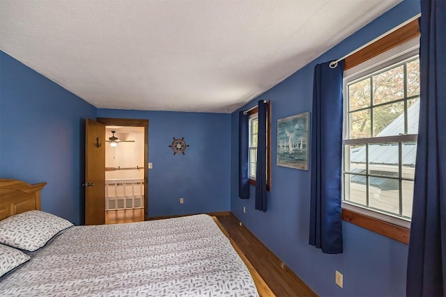 bedroom featuring a textured ceiling, ensuite bathroom, and dark hardwood / wood-style floors