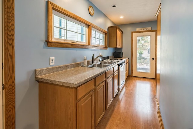 kitchen featuring light wood-type flooring, sink, and white range with gas cooktop