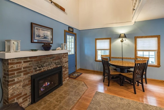 dining room featuring wood-type flooring and a brick fireplace