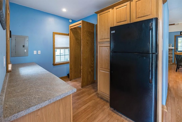 kitchen featuring electric panel, black fridge, and light hardwood / wood-style floors