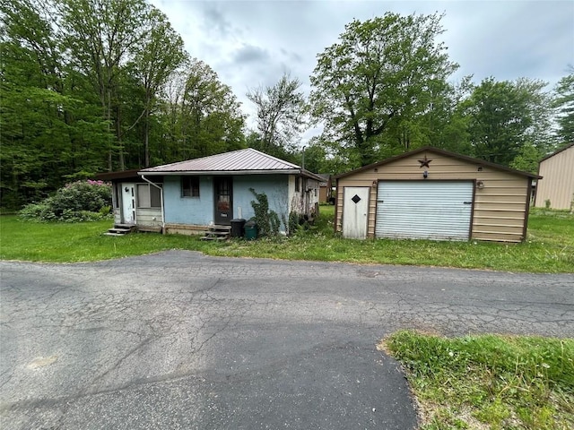 2892 Township Rd, Linesville, PA 16424 - view of front of house with an outdoor structure, a detached garage, metal roof, entry steps, and a front lawn