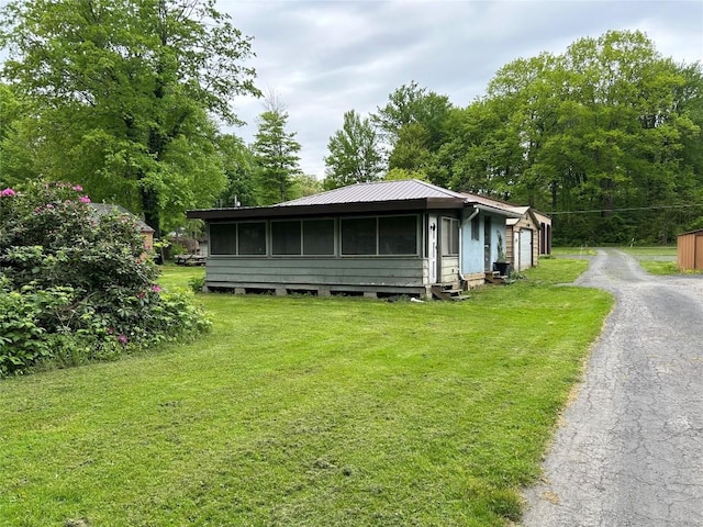 2892 Township Rd, Linesville, PA 16424 - view of property exterior with a yard, a sunroom, a garage, asphalt driveway, and an outbuilding