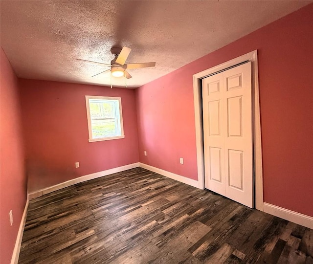 unfurnished bedroom with ceiling fan, baseboards, dark wood-style flooring, and a textured ceiling