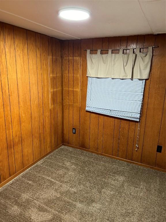 carpeted empty room featuring wooden walls