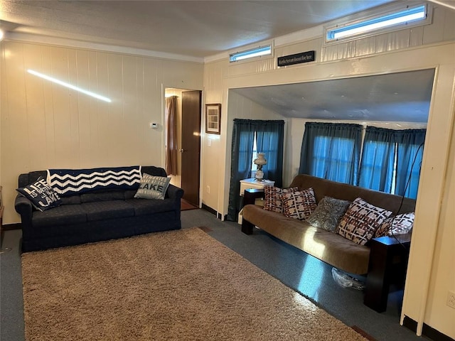 living room featuring dark colored carpet and wood walls