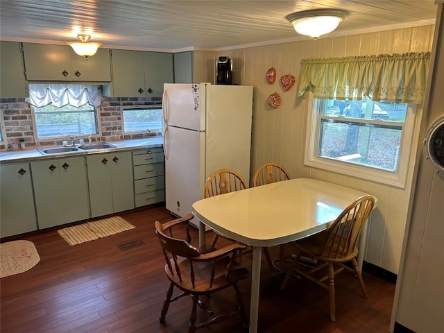 dining space featuring dark hardwood / wood-style flooring, crown molding, sink, and plenty of natural light