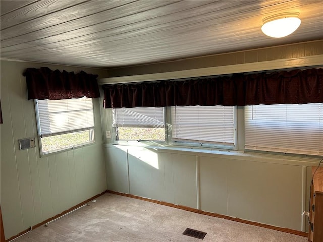 interior space featuring light colored carpet, wooden ceiling, and wood walls