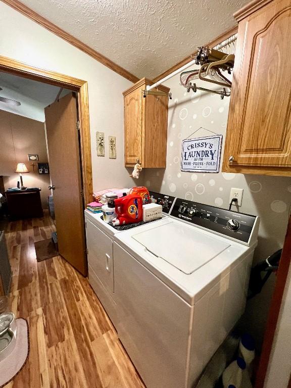 washroom featuring cabinets, separate washer and dryer, crown molding, wood-type flooring, and a textured ceiling