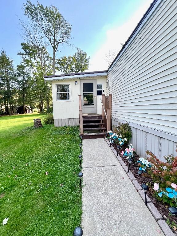 view of exterior entry featuring a lawn