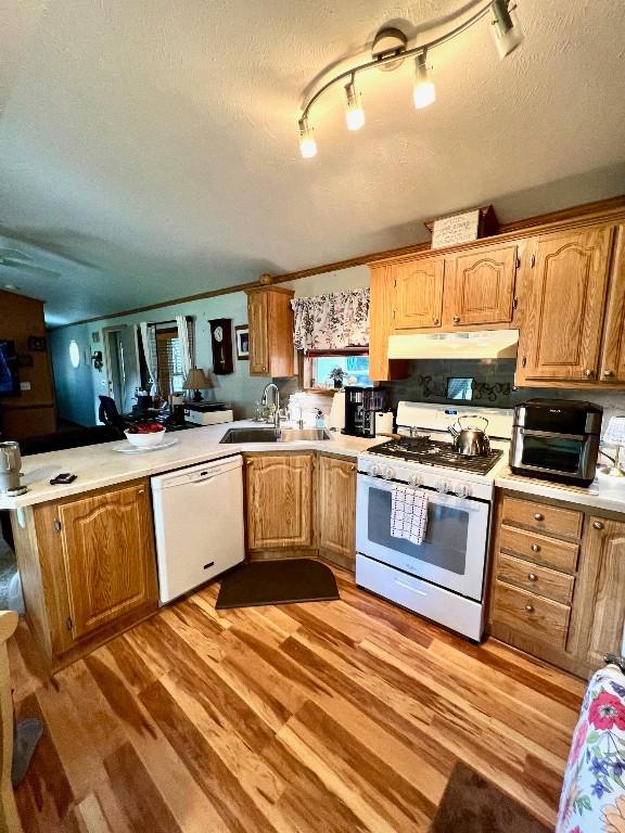 kitchen with a textured ceiling, white appliances, crown molding, sink, and light hardwood / wood-style flooring