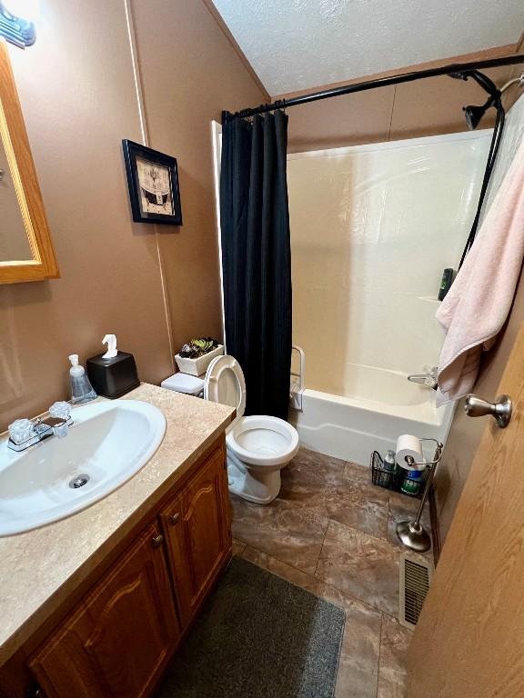 full bathroom with a textured ceiling, vanity, toilet, and shower / bath combo with shower curtain