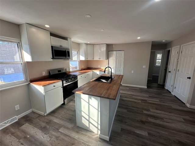 kitchen featuring stainless steel appliances, sink, butcher block countertops, and white cabinets